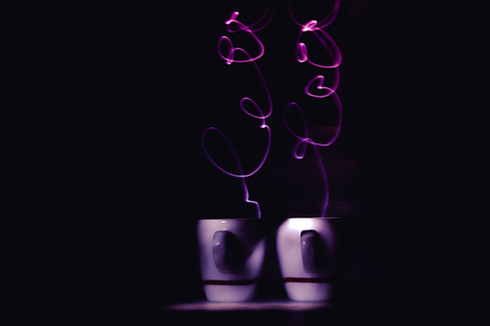 Light brush, lightgraphy or lightpainting of purple color steam from coffee cups - copyspace.の写真素材