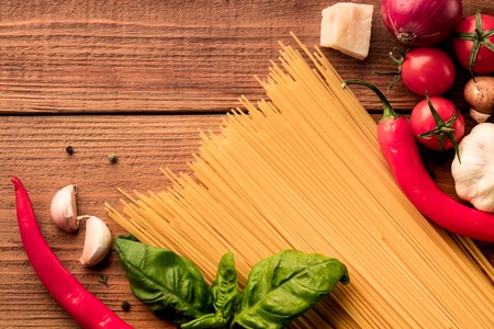 Italian pasta spaghetti with fresh vegetables and spices - top view on wooden backgroundの写真素材