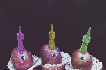 Funny unicorn faces from space purple eggs with eyes and colorful shining horns colored in cosmic space paint. Easter. Copyspace on black backgroundの写真素材