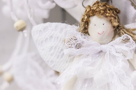 Cute angel textile handmade doll with curly hair, white lace wings and dress. Soft focus Christmas decorative backgroundの写真素材