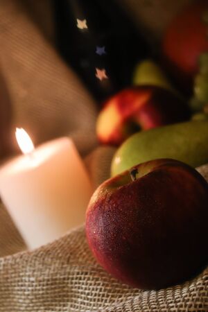 Happy Thanksgiving post card with autumn still life. Red apples and green pears with soft candlelight on table sackclothの写真素材