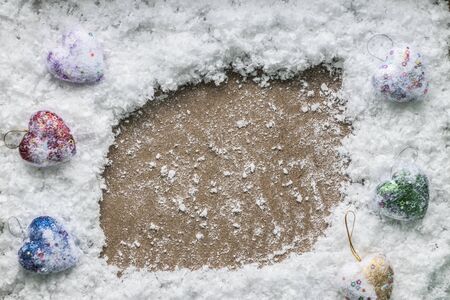 Winter holidays frame of artificial fluffy snow and christmas decoration toy hearts with glitter with space for text. Top view.の写真素材