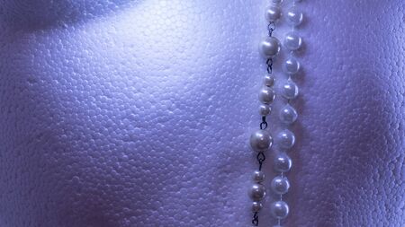 textured white background with blue light shades and 2 strips of pearl necklaces.