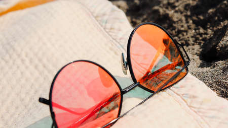 Red stylish woman Sunglasseson a beach blanket with reflection of summer beach with black sand and Tyrrhenian sea. Capri, Italyの写真素材