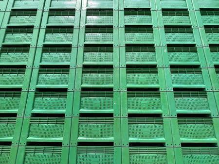 Tall stack of green color new plastic packaging crates background.