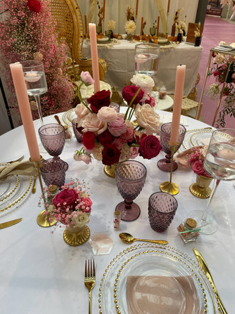 Festive table setting in pink purple red style with candles and flowers.の写真素材