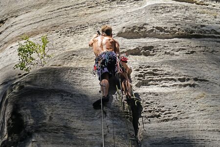 Rock climber working with hammer on sandstone wallの写真素材
