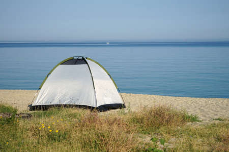 Tent pitched on the beautiful beach with morning calm sea view, romantic camping or backpacking summer holidayの写真素材