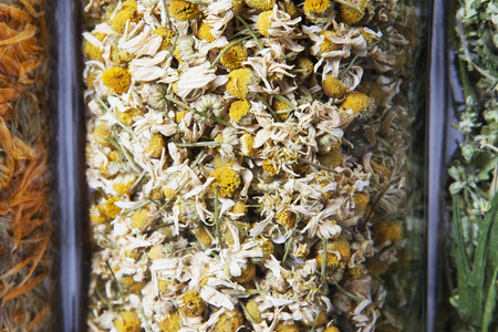 Dried chamomile herb inside a glass jar. Herbs and plants for tea.の写真素材