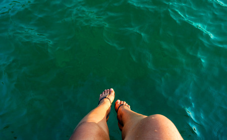 relax motion woman leg sitting over the sea on the briged at seasideの写真素材