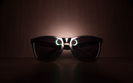 black Sunglasses on wood floor with led ring light reflectの写真素材