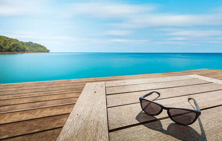 black sunglass on wood terrace at seaside with nice blue skyの写真素材