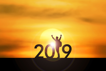 Happy New year 2019 concept : Backpacker standing and raise the hand up on sunset time