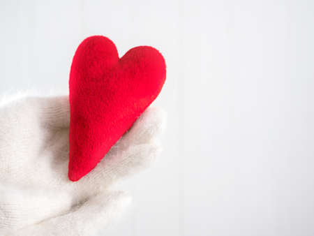 Red velvet heart handmade in the hands of white winter glovesの写真素材