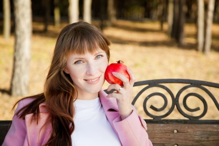 Beautiful young woman with fruit in park の写真素材