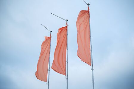 three red flags in the blue sky flutter in the wind