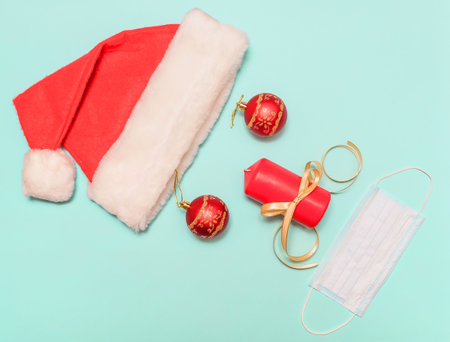 On a blue background, a santa claus hat, balls instead of eyes, a candle instead of a nose. For design. Protective mask instead of the mouth.の写真素材
