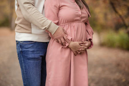 Young couple, pregnant wife, outdoors, hugging.の写真素材
