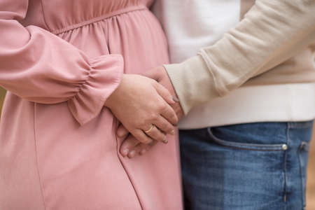 Young couple, pregnant wife, outdoors, hugging.の写真素材
