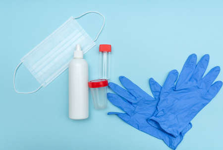 Medical mask to protect against corona virus. On a blue background. Gloves. Analysis container. Close-up. Disinfection bottle.の写真素材