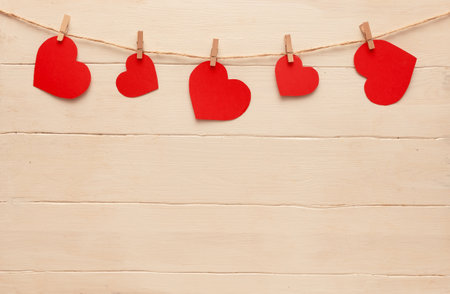 Red hearts on a rope with clothespins, on a white wooden background. Place for text. Banner.の写真素材