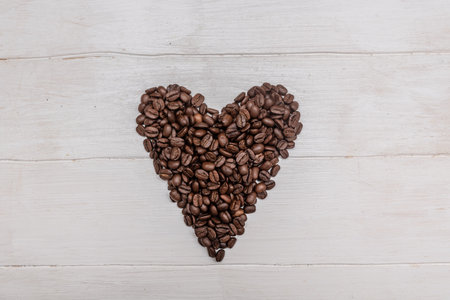 Black coffee beans. In the form of a heart. On a white wooden background. Minimalism. For the design and writing of text. Valentine's Day.の写真素材