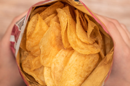 Hands hold a bag of potato chips. Junk food made from cholesterol. Salty and crispy. Fast food...