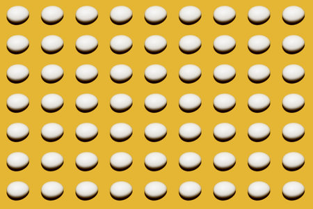 White egg on a yellow background. Colorful pattern of chicken white eggs. Pattern on a colored background.の写真素材