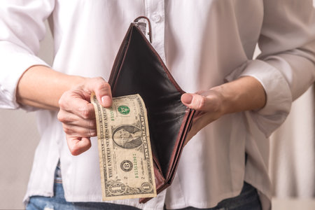 Female hands in a white shirt are holding a wallet with money.