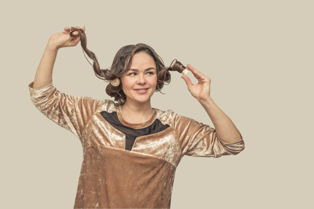 Beautiful happy woman at home winds her hair with curlers.