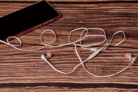 Phone on a brown background. The phone has white headphones. Close-up.の写真素材