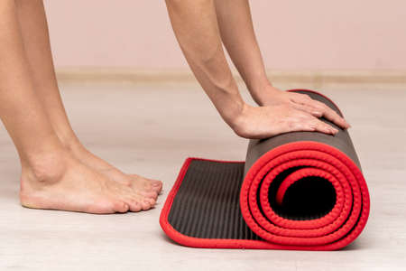 Close-up in the gym. Hands unroll the carpet. Exercise fitness. Healthy lifestyle.の写真素材
