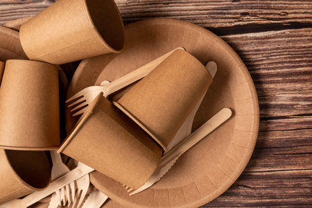 The craft package contains disposable tableware, forks, knives and glasses. On a wooden brown background.の写真素材