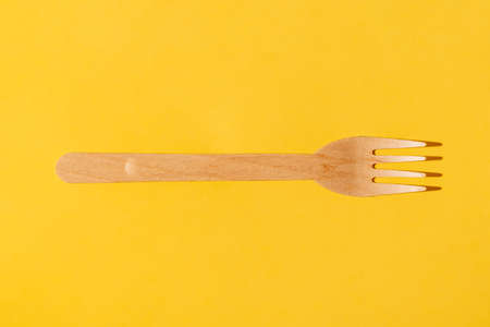 Wooden brown disposable tableware. Fork pattern. On a yellow background. Environmentally friendly...