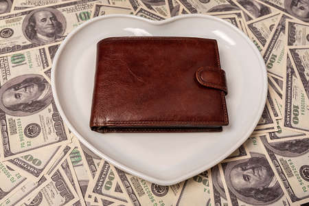 Empty wallet on a white plate in the shape of a heart. Money on the table. Business concept.の写真素材