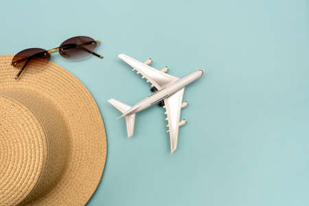 Traveling by plane. Layout on a blue background. Hat, plane, glasses. Flat lay.