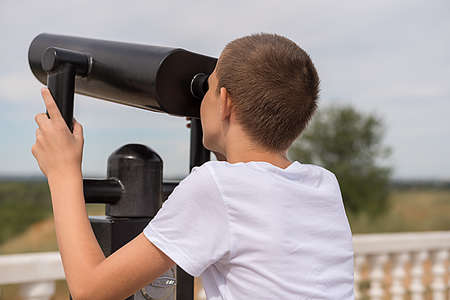 A teenager in a white T-shirt next to a telescope. Study of the route. Close-up.の写真素材