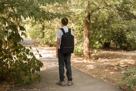 Happy teenager stands in the street in autumn with a briefcase on his shoulders. Back to school...