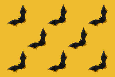 Pattern. Black paper bat on a yellow background. Halloween concept. With a hard black shadow. View from above.の写真素材