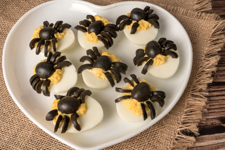 Halloween table decoration. Spiders made from eggs and olives. Party snack. On a white plate.の写真素材