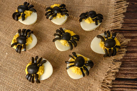 Halloween table decoration. Spiders made from eggs and olives. Party snack. On sackcloth. Close-up.の写真素材