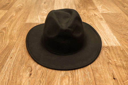 Black mens stylish felt hat. Lies on the wooden floor.の写真素材