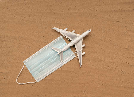 Passenger white plane on the sand with a mask. Airplane flight advertising concept.の写真素材