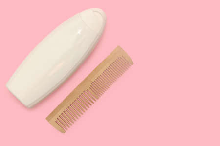 White bottle shampoo, wooden comb. Natural organic cosmetics for hair care. pink background.の写真素材