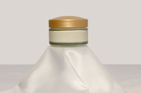 Cream mock-up on a white silk fabric podium. Gentle skin care concept.