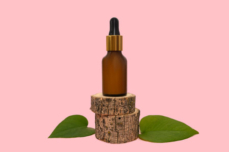 Cosmetic lotion on a wooden podium. green leaves. On a pink background. close-up.の写真素材