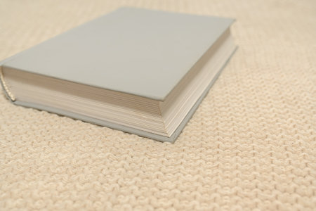 On a white jumper lies a white book. Knitwear texture. autumn concept. For design.