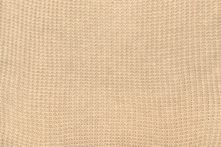 Texture of beige knitwear. Autumn, winter, warm, knitted. jumper for women. close-up.