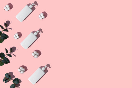 White cream dispenser eucalyptus branch white cotton flowers. Place for text on a pink background.の写真素材