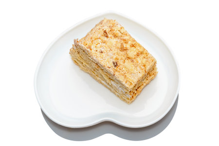 Napoleon cake is a delicious dessert on a white plate in the shape of a heart. On a white background.の写真素材